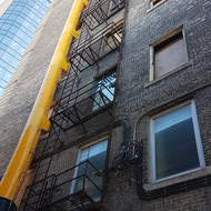 Rear shot of the building and the disposal chute running along side the fire escape.